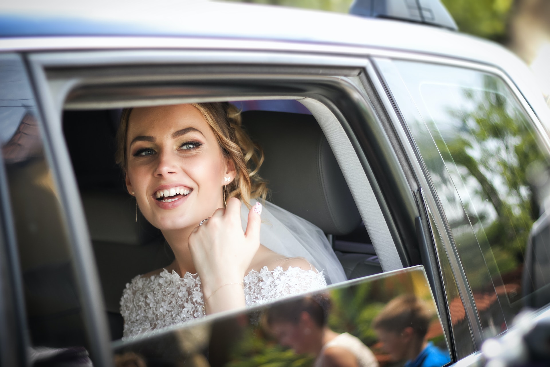 Bride smiling from a chauffeured wedding car